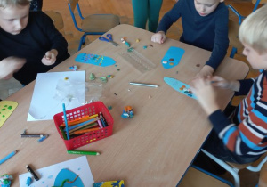 Dzieci ozdabiają kredki wycięte z kolorowego papieru za pomocą kropek z plasteliny