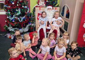 Dzieci pozują do zdjęcia grupowego ze Świętym Mikołajem.