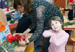 Mama z Helenką odkladają na półkę wykonany stroik świąteczny