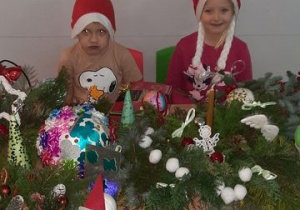 Maja i Oluś siedzą za stołem z ozdobami świątecznymi
