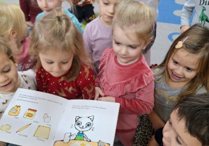 Dzieci słuchają książeczki "Kicia Kocia gotuje".