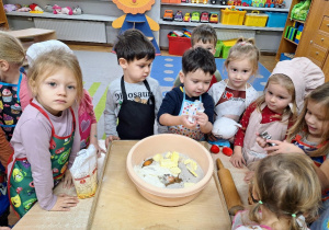 Dzieci dodają do miski produkty potrzebne do pieczenia ciasteczek.