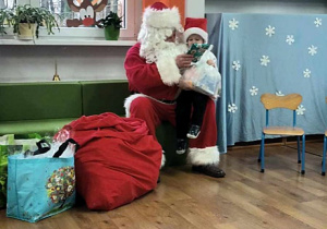 Mikołaj obdarowuje dzieci prezentami.