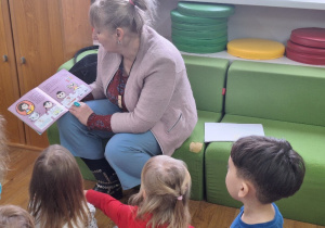 Pani Bibliotekarka czyta dzieciom książeczkę.