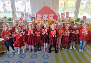 Dzieci pozują do zdjęcia grupowego z czerwonymi serduszkami - Walentynkami.