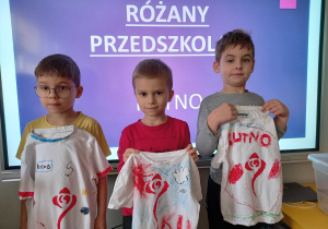 Tymon, Staś W. i Olek L. prezentują swoje koszulki