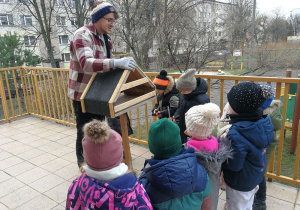 Dzieci wspólnie z tatą Alicji i Janka montują karmnik.