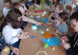 Rodzice z dziećmi wykonują wielkanocne ozdoby