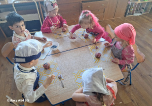 Dzieci dekorują upieczone babeczki.