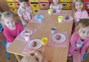Dzieci siedzą przy stolikach gotowe do degustacji przygotowanych przez siebie babeczek.