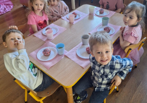 Dzieci siedzą przy stolikach gotowe do degustacji przygotowanych przez siebie babeczek.