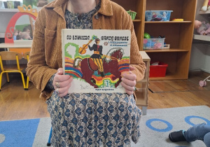 Pani Bibliotekarka prezentuje dzieciom książkę o zwyczajach ludowych.