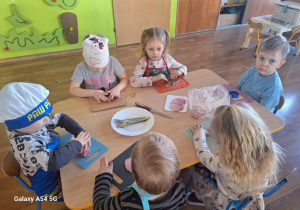 Dzieci przygotowują wielkanocną sałatkę z szynki i sera, wykrawają kształty zwierzątek z wykorzystaniem foremek do ciastek.