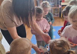 Mama Asi, Helenki i Zosi częstuje dzieci słodką niespodzianką.