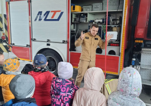 Strażak opowiada dzieciom o wyposażeniu wozu strażackiego