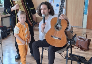 Carlos opowiada Oskarowi i dzieciom o gitarze.