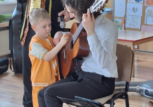 Oskar uczy się grać na gitarze.