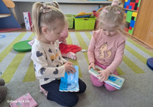Dziewczynki oglądają ilustracje w książce.