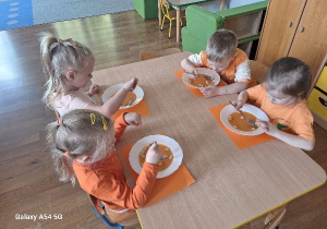 Dzieci jedzą na obiad zupę marchewkową.