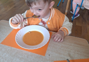 Oluś zjada na obiad zupę marchewkową.