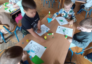Dzieci ozdabiają kontury Ziemi za pomocą wydzieranki z papieru