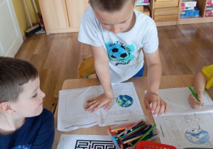 Maciek z Tymkiem wykonują zadania z ekologicznej książeczki