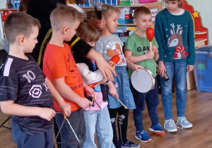 Szóstka dzieci trzyma w ręku instrumenty perkusyjne, Pan Bachman pokazuje jak się gra na danym instrumencie