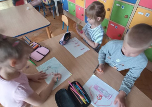 Dzieci siedzą przy stoliku i rysują ilustracje do bajki "Little Red Riding Hood"