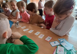 Dzieci odsłuchują melodię graną przez robota zgodnie z wybraną przez siebie kolejnością kart
