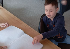 Tymek dotyka książkę pisanej pismem Braille'a