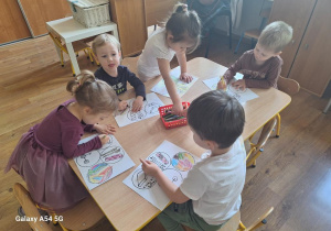 Dzieci pracują przy stolikach - wykonują "Książeczkę na nudę".