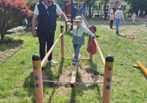 Oluś w towarzystwie Taty przechodzi po równoważni.