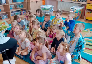 Dzieci słuchają książeczki i zadają pytania związane z jej treścią.