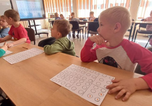 Dzieci zamalowują inicjały swojego imienia i nazwiska zgodnie z kodem Braille'a