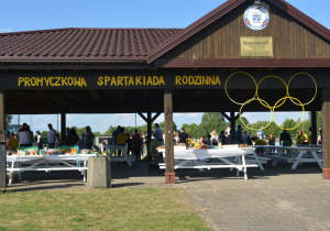 Napis "Promyczkowa spartakiada rodzinna" i żółte koła olimpijskie