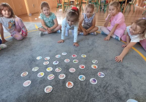 Gra "Cupcakes" w języku angielskim - dzieci siedzą w kole, rzucają 2 kostkami z kolorami i szukają babeczek, które spełniają dane kryteria, przy okazji utrwalając nazwy kolorów w języku obcym